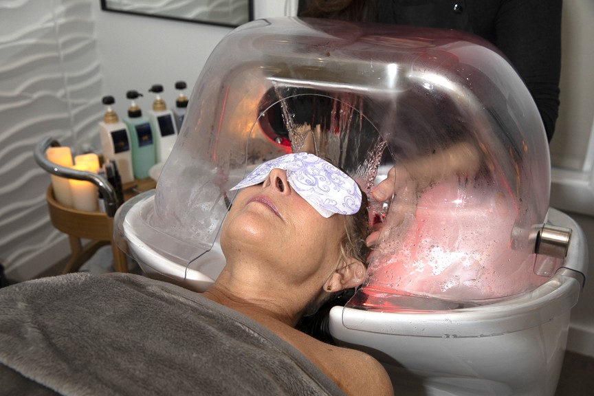 Client receiving a relaxing halo waterfall rinse in the vaporizing dome by Maletti